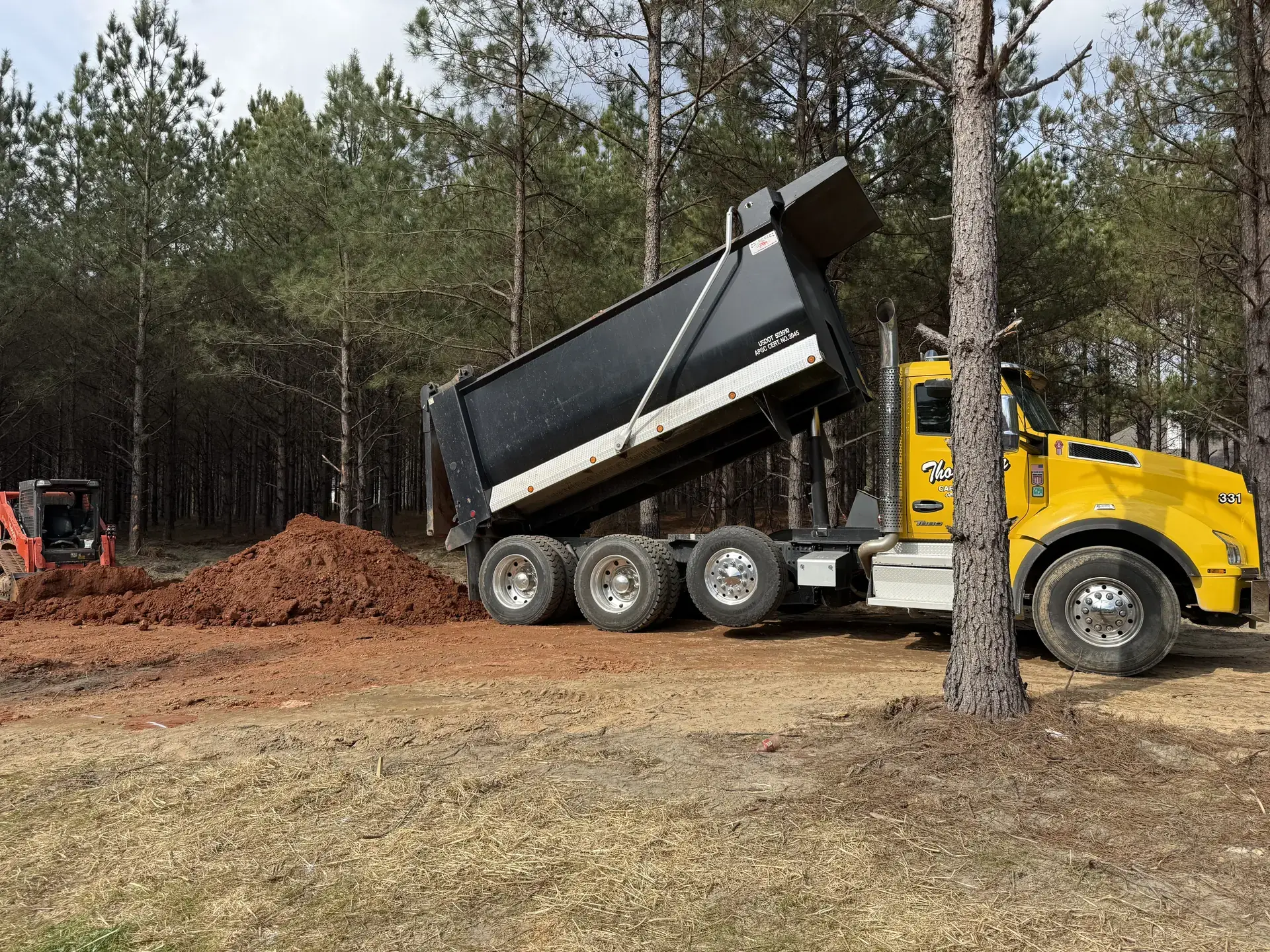 Dump truck delivering fill dirt to a rural property
